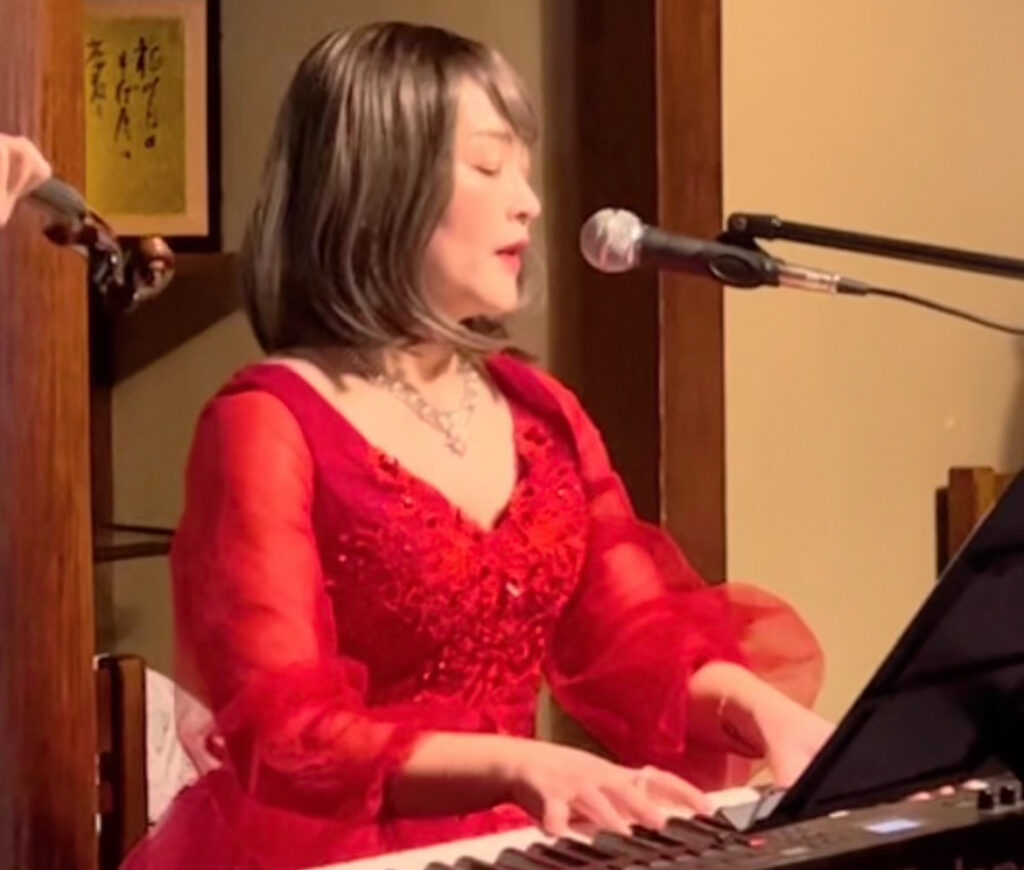 赤いドレスでピアノを弾きながら歌うAkika